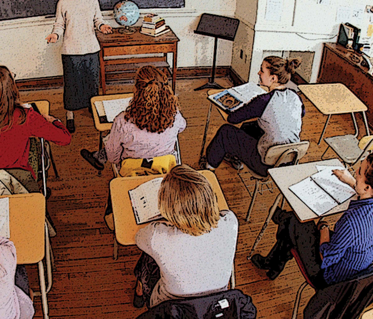 A classroom of students listen to their teacher's lesson.