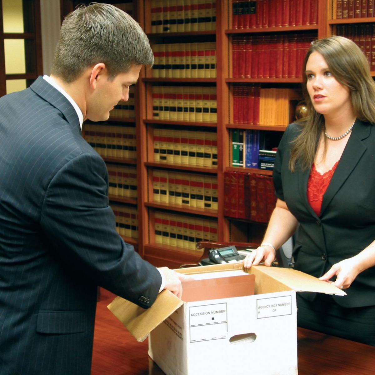 A female lawyer shares documents with a male lawyer during discovery.