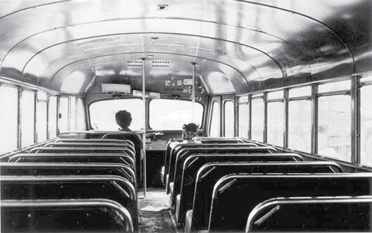 A photo of the inside of a school bus with the driver and one student shown at the front of the cab