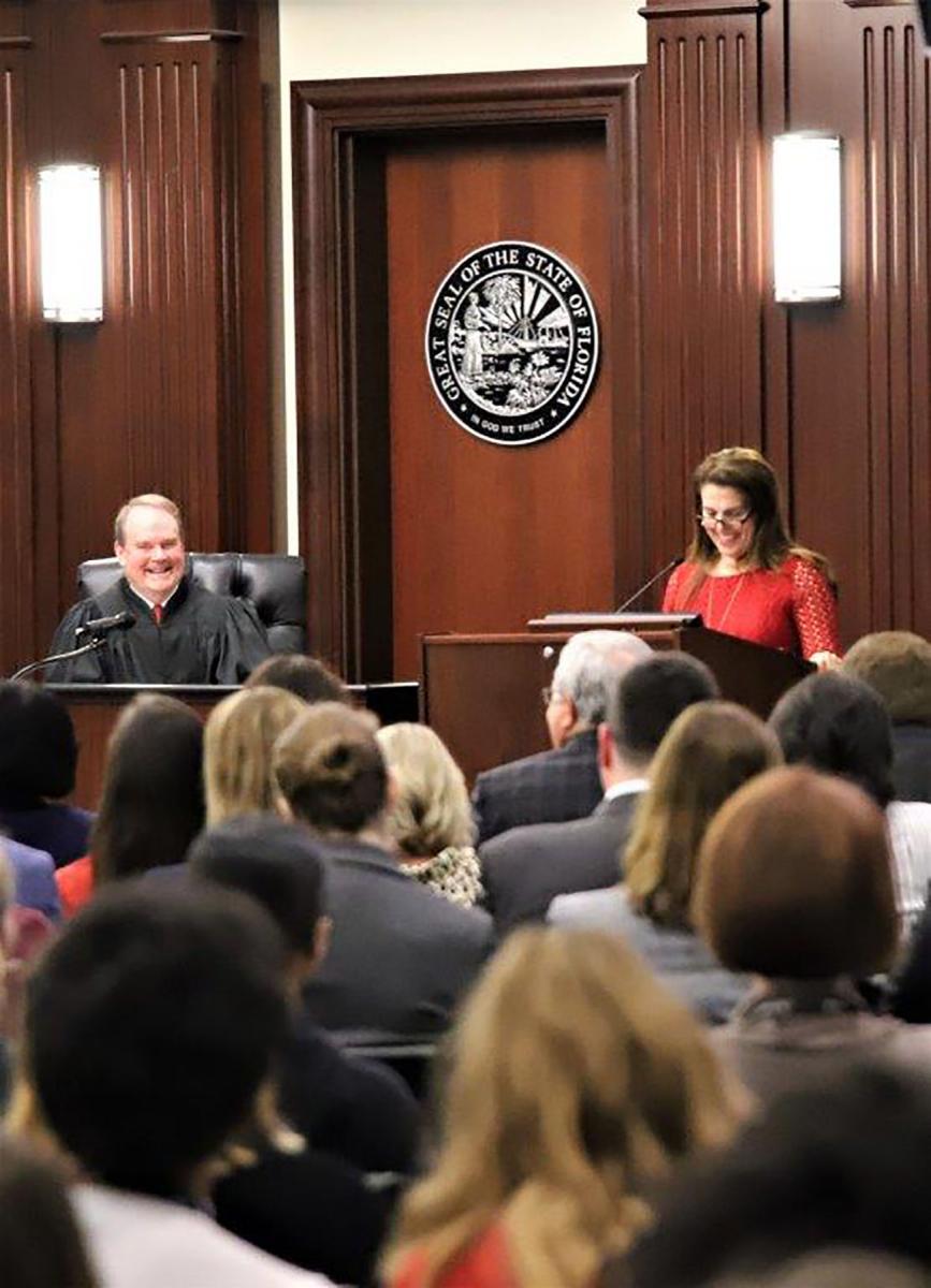 Judge Corrigan, who presided at the naturalization ceremony, listening to the featured speaker at the ceremony, Judge Tatiana Salvador, Circuit Judge, Fourth Judicial Circuit of Florida. Judge Corrigan, who presided at the naturalization ceremony, listening to the featured speaker at the ceremony, Judge Tatiana Salvador, Circuit Judge, Fourth Judicial Circuit of Florida.